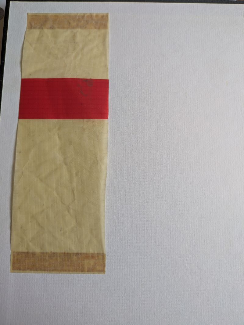 Picture of red and yellow balloon fabric sample stuck on white paper inside front book cover .